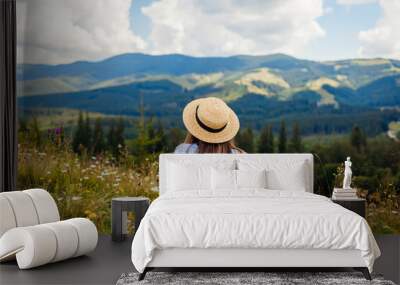 Traveling in summer Ukraine. Trip to Carpathian mountains. Woman tourist relaxing in flowers admiring view Wall mural