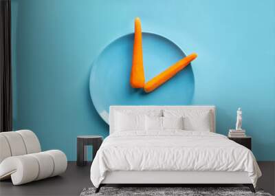 Intermittent fasting. Food and clock hands. Carrots on a blue plate flat lay and blue background. 20: 4 fasting diet concept. Wall mural