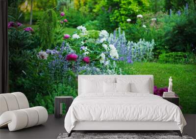 beautiful english style cottage garden view in summer with blooming peonies and companions - stachys, catnip, heranium, iris sibirica. Composition in white and blue tones. Landscape design. Wall mural