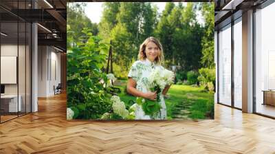 beautiful young woman gardener posing with hydrangea flowers in summer cottage garden Wall mural