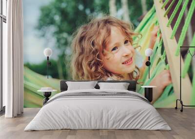 happy child girl relaxing in hammock on summer camp in forest. Outdoor seasonal activities for kids. Wall mural