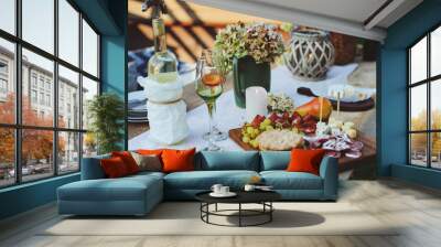 summer outdoor garden table setting with flowers, candles, white wine, cheese and fruits Wall mural