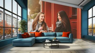 two happy girl friends talking and drinking coffee in autumn city in cafe. Meeting of good friends, young fashionable students with natural make up. Wall mural