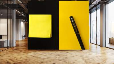 Sticky note and pen isolated over yellow and black background Wall mural