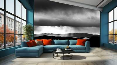 Sunrays coming over mountains beneath moody clouds Wall mural