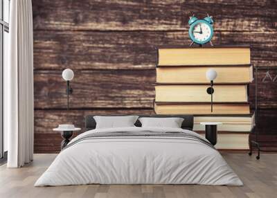 Alarm clock and books on wooden table. Wall mural