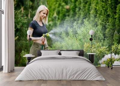 blonde girl watering her garden in summer Wall mural