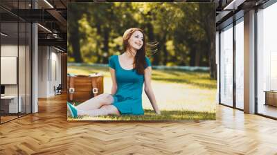 Redhead girl with suitcase in the park. Summertime season Wall mural