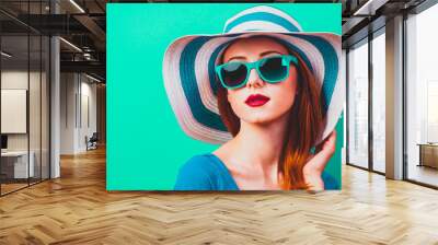 style redhead girl with makeup in blue hat and sunglasses on green background isolaed Wall mural