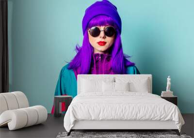 Stylish white girl with purple hair, 80s tracksuit and sunglasses on blue background Wall mural