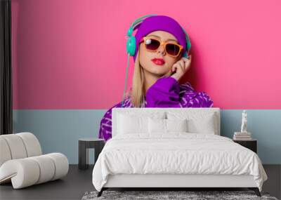 Young blonde girl in 90s sports jacket and hat on pink and blue background. Wall mural