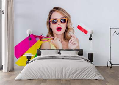 young redhead girl in sunglasses with shopping bags and polish flag on white background Wall mural