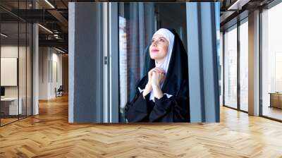 Young smiling nun near window Wall mural