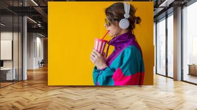 Young woman in 90s style clothes with cup and headphones Wall mural