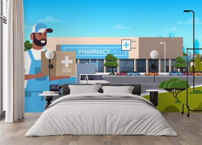 deliveryman carrying medical products in cardboard box with cross sign modern drugstore front view pharmacy store building exterior medicine healthcare delivery service concept horizontal portrait Wall mural