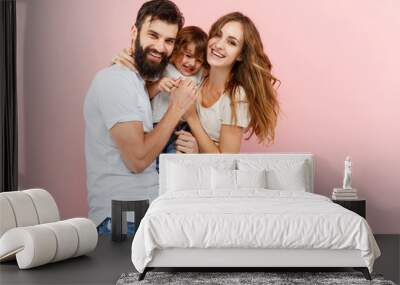 A happy family on pink studio background. The father, mother and son posing together Wall mural