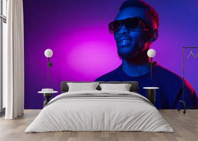 African-american young man's portrait on dark studio background in neon. Concept of human emotions, facial expression, youth, sales, ad. Wall mural