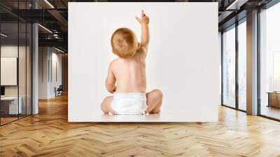 Back view image of little baby, child, toddler sitting in diaper against white studio background. Curious baby. Concept of childhood, newborn lifestyle, happiness, care. Copy space for ad Wall mural