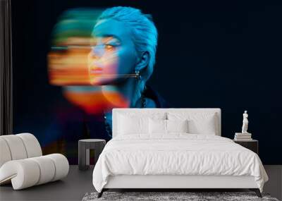 Blurred portrait of young blonde girl with neon colored face posing over dark background in blue neon lights. Concept of art, modern style, cyberpunk, futurism and creativity Wall mural