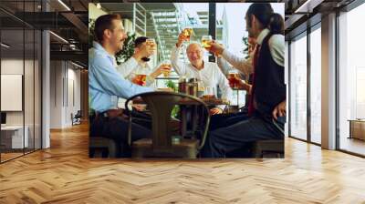 Business professional, smiling men in formal wear meeting at outdoor bar and raising glasses of beer in celebratory toast. Cheers to successful partnership. Concept of business, Oktoberfest, team Wall mural