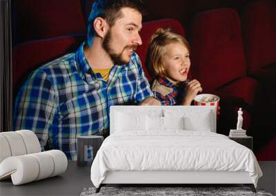 Caucasian father and son watching a film at a movie theater, house or cinema. Look expressive, astonished and emotional. Sitting alone and having fun. Relation, love, family, childhood, weekend. Wall mural