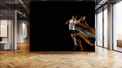 Caucasian young handball player in action and motion in mixed lights over black studio background. Fit male professional sportsman. Concept of sport, movement, energy, dynamic, healthy lifestyle. Wall mural