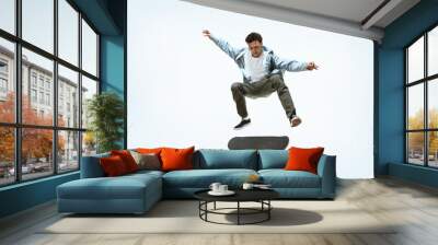 Caucasian young skateboarder riding isolated on a white studio background. Man in casual clothing training, jumping, practicing in motion. Concept of hobby, healthy lifestyle, youth, action, movement. Wall mural