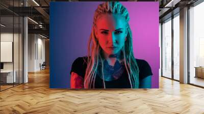 Caucasian young woman's portrait on gradient background in neon light. Beautiful female model with unusual look. Concept of human emotions, facial expression, sales, ad. Looking at camera serious. Wall mural