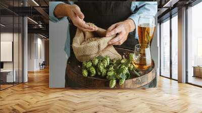 Close up of confident senior man brewer with self crafted beer in glass on wooden barrel on grey background. Owner of factory presented his products of brewing. Oktoberfest, drink, alcohol, industry. Wall mural