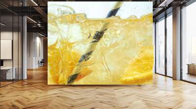 Close up of lemon slices in stirring the lemonade and ice cubes on background. Texture of cooling sweet summer's drink with macro bubbles on the glass wall. Fizzing or floating up to top of surface. Wall mural