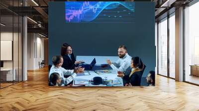 Colleagues in corporate setting analyze market data while examining a digital stock chart displayed on a monitor. Concept of business, entrepreneurship, trade market, economics, finances Wall mural