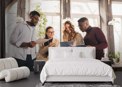 Colleagues working together in modern office using devices and gadgets during negotiations Wall mural