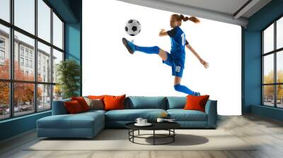 Concentrated teen girl, soccer player in blue uniform kicking ball in motion in jump isolated on white studio background. Concept of sport, active and healthy lifestyle, childhood, school, hobby Wall mural