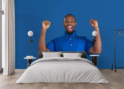 Crazy happy winner. Monochrome portrait of young african-american man isolated on blue studio background. Beautiful male model. Human emotions, facial expression, sales, ad concept. Youth culture. Wall mural