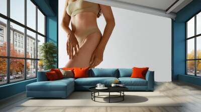 Cropped image of slim, healthy female body, legs over grey studio background. Model posing in underwear. Depilation, epilation. Concept of female beauty, body care, fitness, sport, health, figure, ad Wall mural