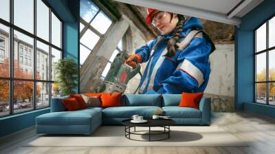 Destroying gender stereotypes. Woman wearing helmet using different male work tools. Gender equality. Girl working at flat remodeling. Building, repair and renovation. woman in the male profession Wall mural