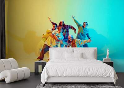 Diverse people, dancers in colorful casual clothes, standing in dynamic jumping pose, performing over gradient green yellow background in neon. Concept of modern dance style, active lifestyle, youth Wall mural