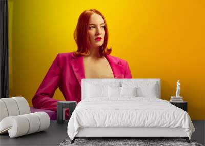 Drink aesthetics. Young redhead woman in pink jacket holding glass with champagne over yellow background Wall mural