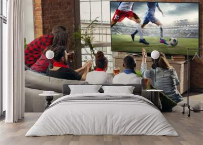 Excited, happy big group of young people watching sport match together on the couch at home. Wall mural