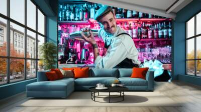 Expert barman is making cocktail at night club or bar. Glass of fiery cocktail on the bar counter against the background of bartenders hands with fire. Barman day concept Wall mural