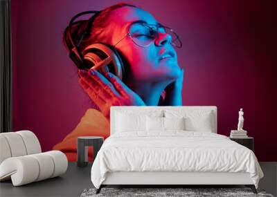 Fashion pretty woman with headphones listening to music over red neon background at studio. Wall mural