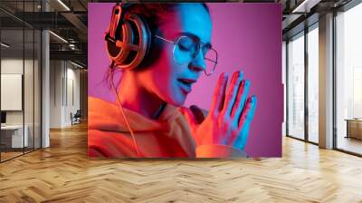 Fashion pretty woman with headphones listening to music over red neon background at studio. Wall mural