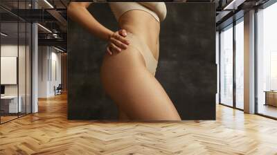 Fitness body of young caucasian woman in nude lingerie isolated on dark vintage studio background. Natural beauty concept. Wall mural