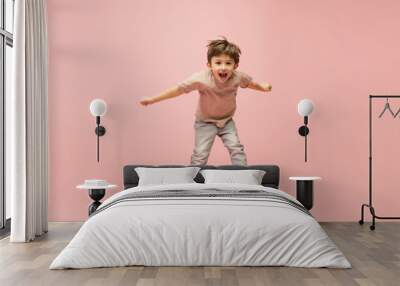 Flying high. Happy, smiley little caucasian boy isolated on pink studio background with copyspace for ad. Looks happy, cheerful. Childhood, education, human emotions, facial expression concept. Wall mural