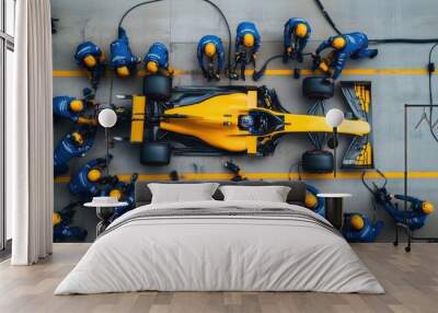 Formula 1 pit crew in blue uniforms surrounds a yellow racing car, performing a pit stop with precision and speed. Wall mural