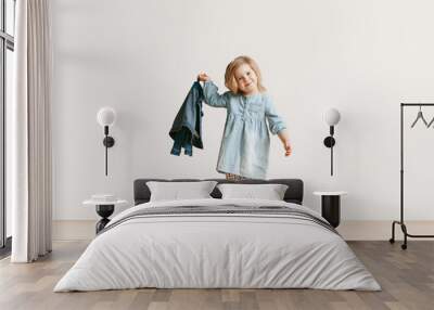 Full length portrait of cute little kid girl in stylish jeans clothes looking at camera and smiling, standing against white studio wall. Kids fashion concept Wall mural