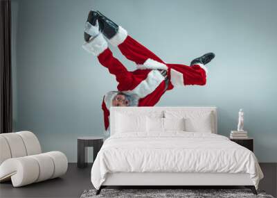 Funny serious guy with christmas hat dancing at studio. New Year Holiday. Christmas, x-mas, winter, gifts concept. Man wearing Santa Claus costume on gray. Copy space. Winter sales. Wall mural