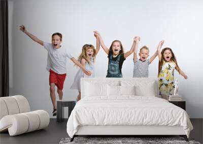 Group of fashion cute preschooler kids friends running together and looking at camera on a white studio background. The friendship, fashion, summer concept. Space for text. Wall mural