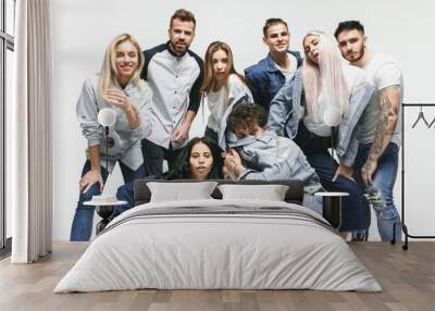 Group of smiling friends in fashionable jeans. The young men and woman posing at studio. The fashion, people, happy, lifestyle, clothes concept Wall mural