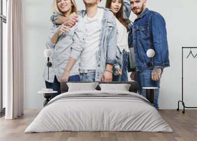 Group of smiling friends in fashionable jeans. The young men and woman posing at studio. The fashion, people, happy, lifestyle, clothes concept Wall mural